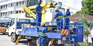 Kenya Power employees repair a transformer.