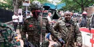 Members of Uganda People's Defence Force (UPDF) walk near a bomb explosion site in Kampala.