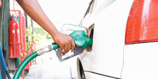 A petrol station attendant fuels a car.