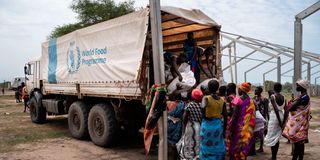 Women unload bags of sorghum from a WFP truck 