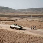 People in Tigray region walk near an abandoned tank 