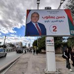 Tunisian women walk underneath an electoral billboard