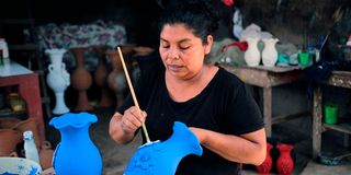 A woman decorates a clay jar