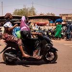 A woman rides a motorcycle in Ouagadougou, Burkina Faso