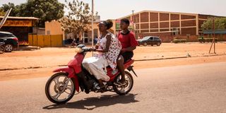 woman rides motorcycle in Ouagadougou, Burkina Faso 
