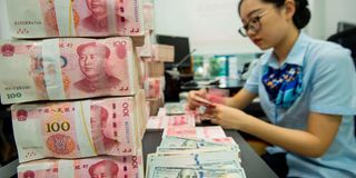 Chinese banker counting yuan and dollars