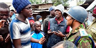 An anti-riot police officer speaks to residents of Mathare