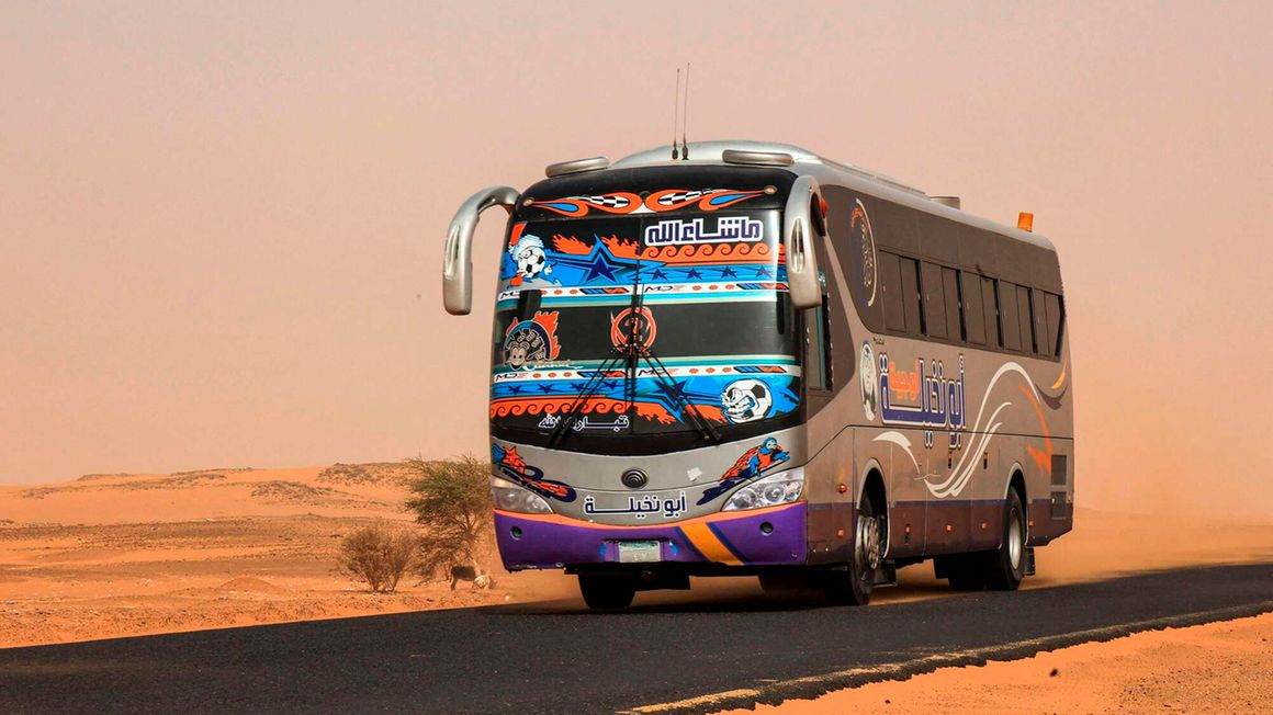 A passenger bus drives along a desert road in al-Gabolab, Sudan
