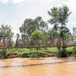 Rwanda floods - People walk over a water bridge 