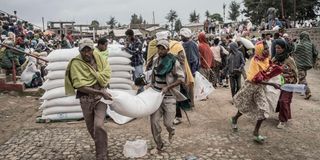 Men carry a sack of wheat during food distribution by WFP 
