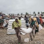 Men carry a sack of wheat during food distribution by WFP 