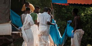 Workers load bodies exhumed from Shakahola