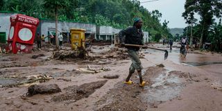 A man removes debris from flooded road in Rwanda